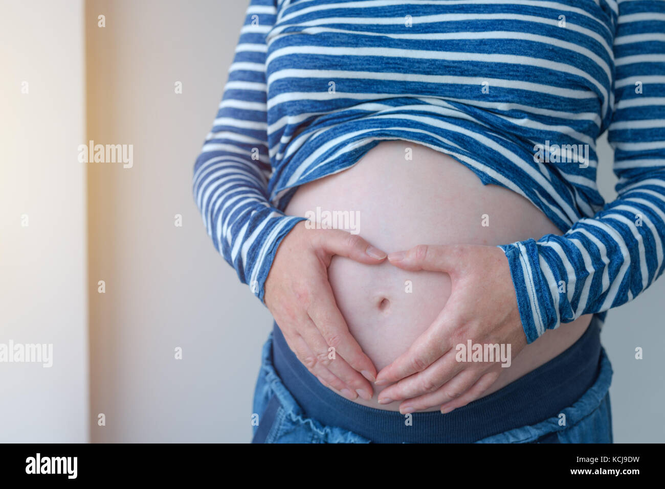 Pregnant woman touching et frottant son ventre, mère de caresser et de stimuler l'abdomen, des profils portrait féminin en cinquième mois ou vingt première semaine de Banque D'Images