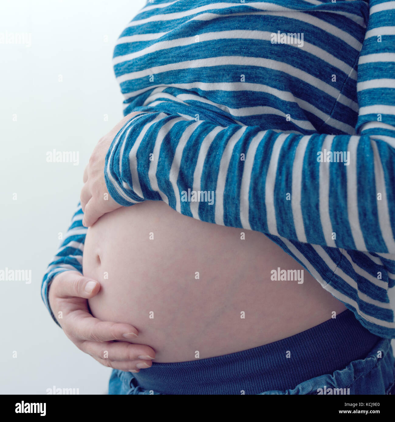 Pregnant woman touching et frottant son ventre, mère de caresser et de stimuler l'abdomen, des profils portrait féminin en cinquième mois ou vingt première semaine de Banque D'Images