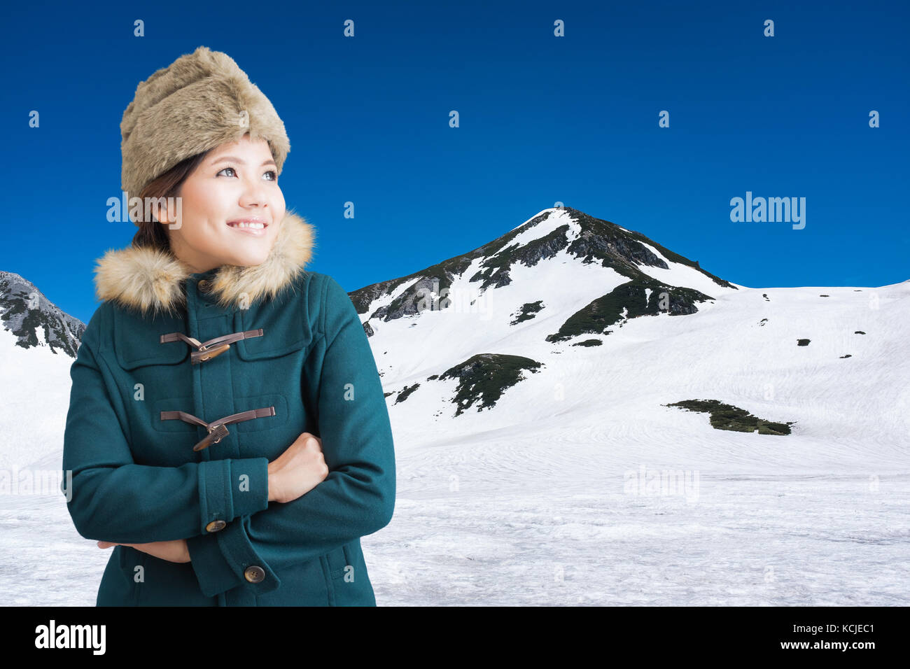 Asian woman wearing green coat with fur hat sur Snow Mountain Banque D'Images
