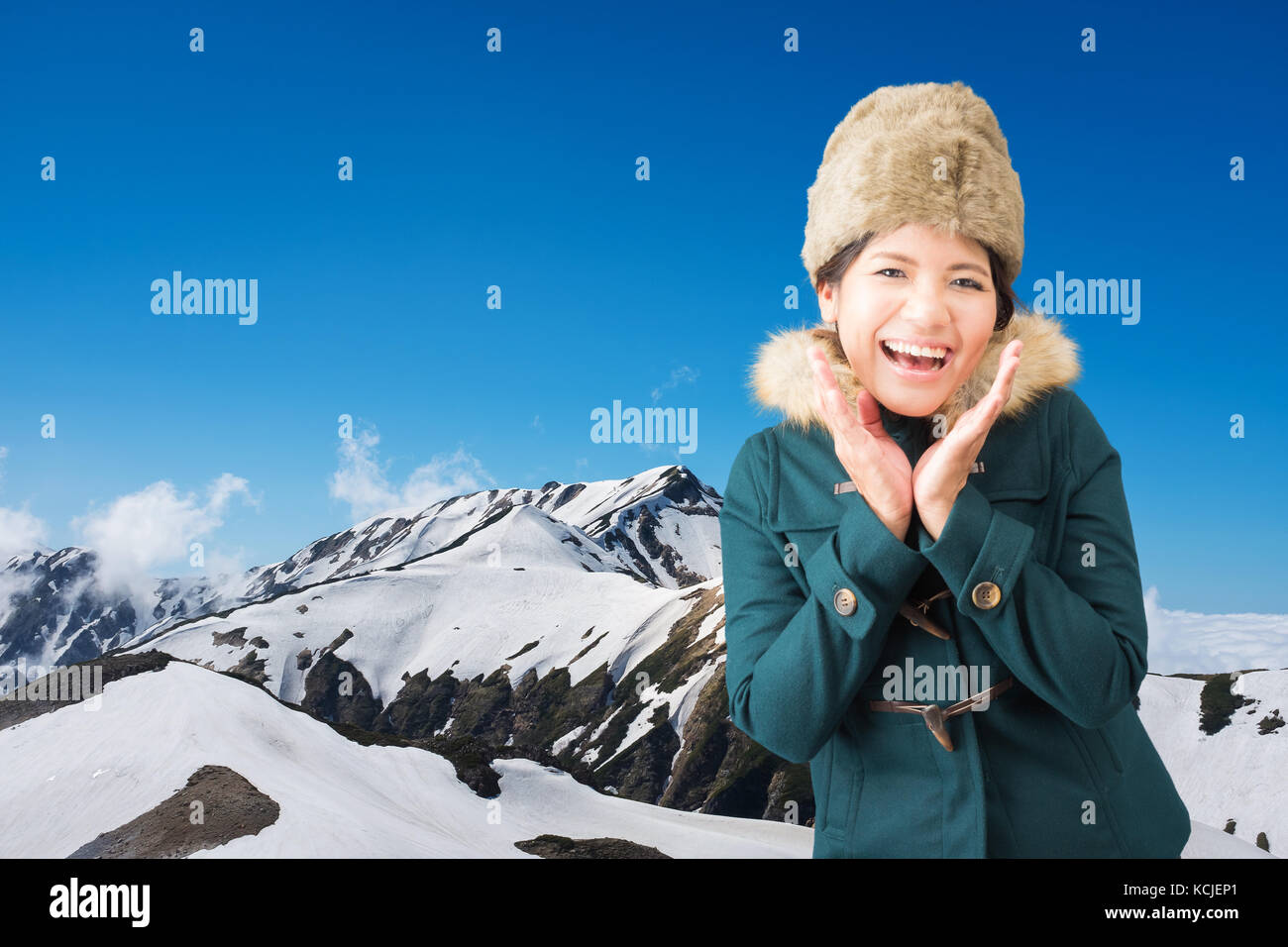 Asian woman wearing green coat with fur hat sur Snow Mountain Banque D'Images