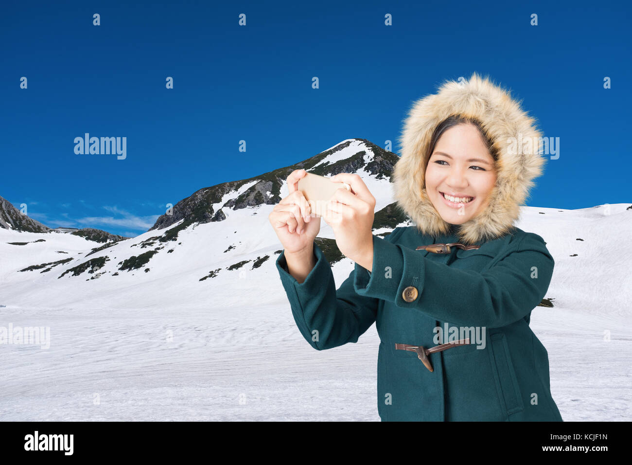 Asian woman wearing green coat with fur hat sur Snow Mountain Banque D'Images