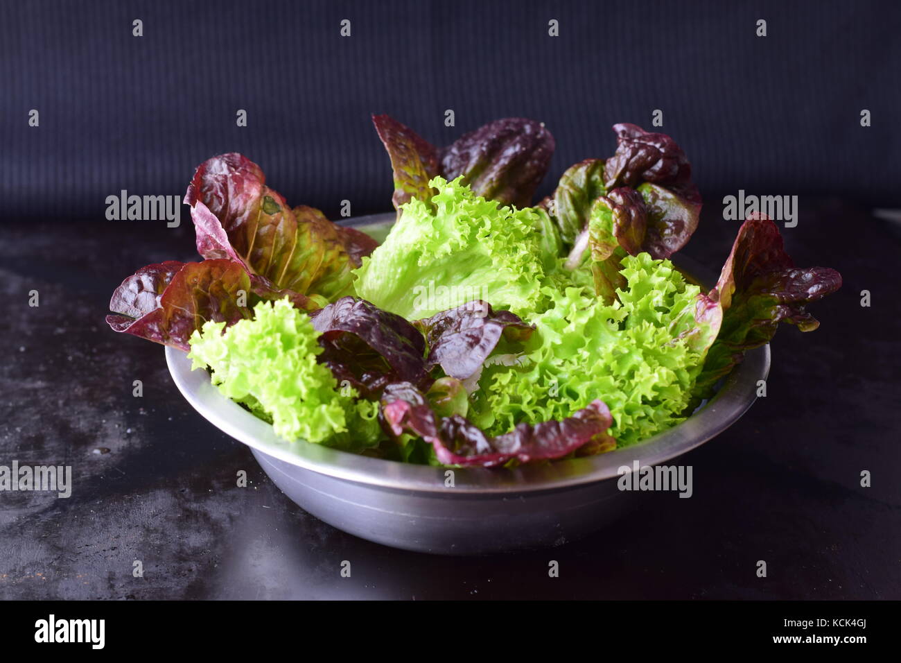 Variété de feuilles de salade dans un bol en métal sur un fond abstrait noir concept sain.. Banque D'Images