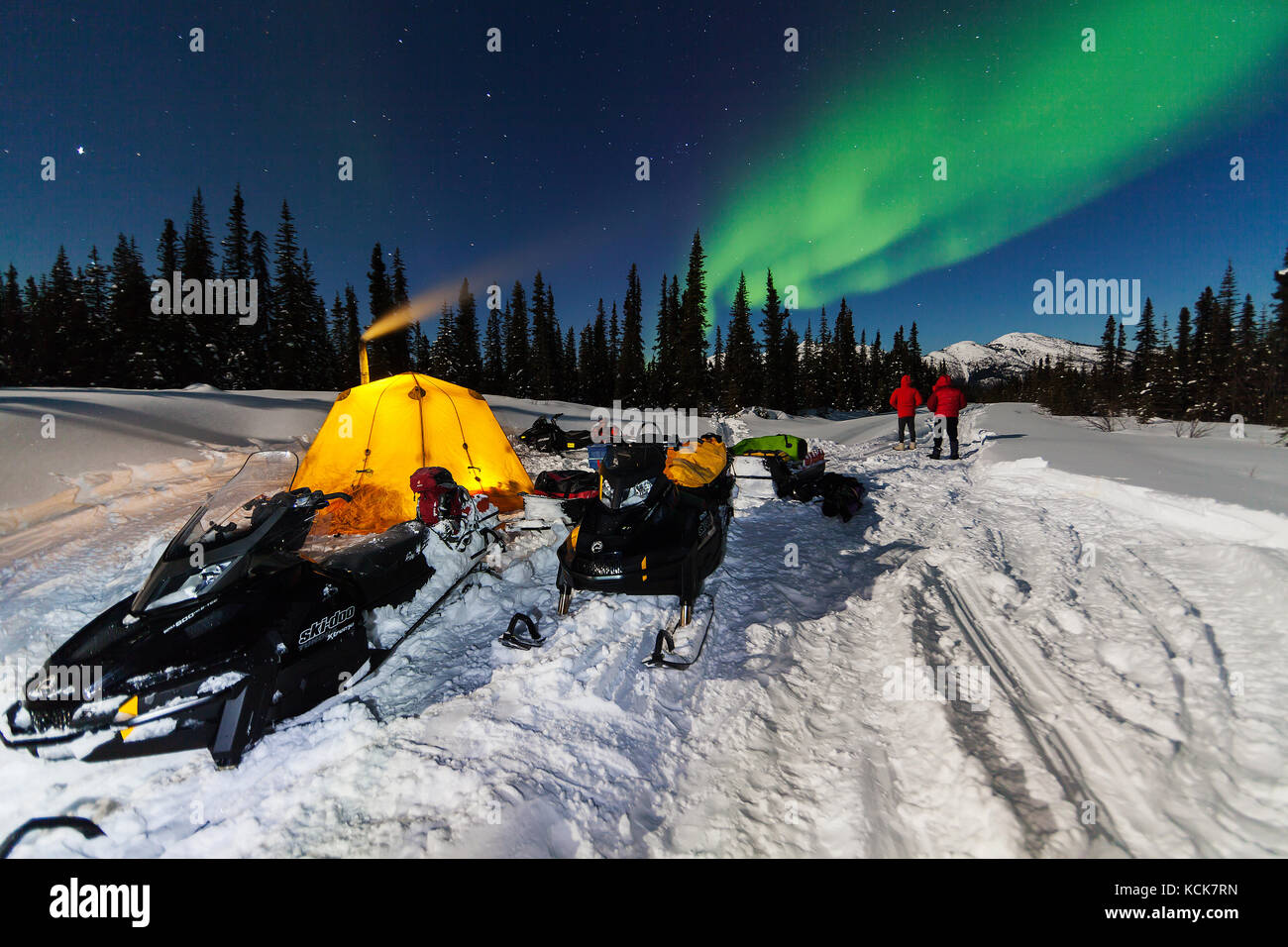 Les motoneigistes qui campent pour la nuit sont accueillis avec des lumières du Nord tout en voyageant le long du sentier du patrimoine de North Canol, territoire du Yukon, Canada Banque D'Images