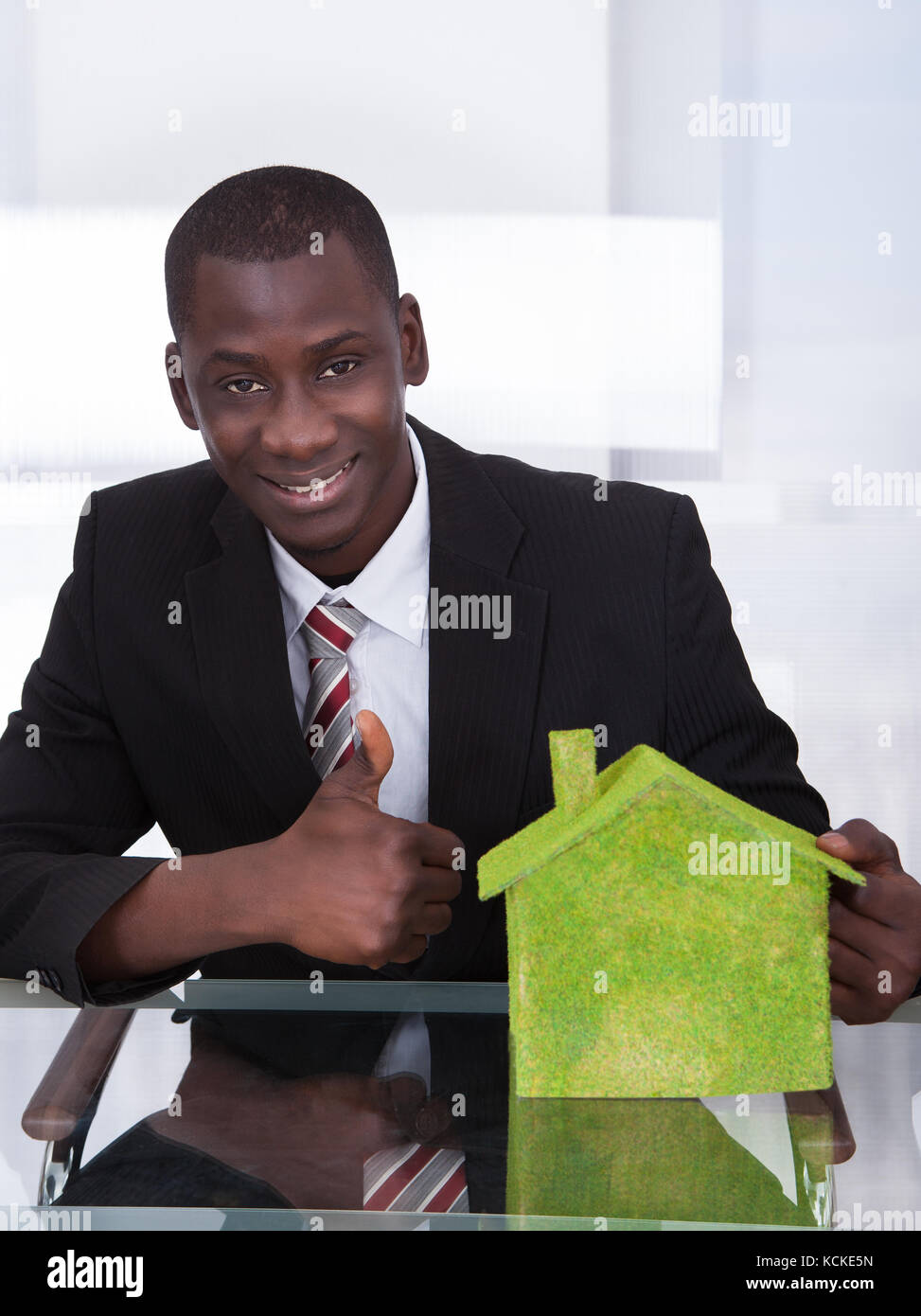 Les jeunes africains businessman sitting at office présentant la maison écologique Banque D'Images