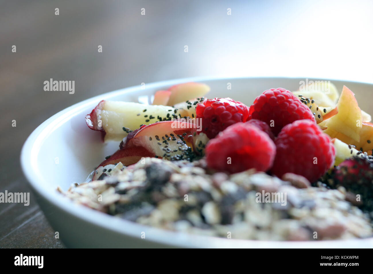 Mélange de fruits et de céréales dans un bol blanc sur la table en bois brun Banque D'Images