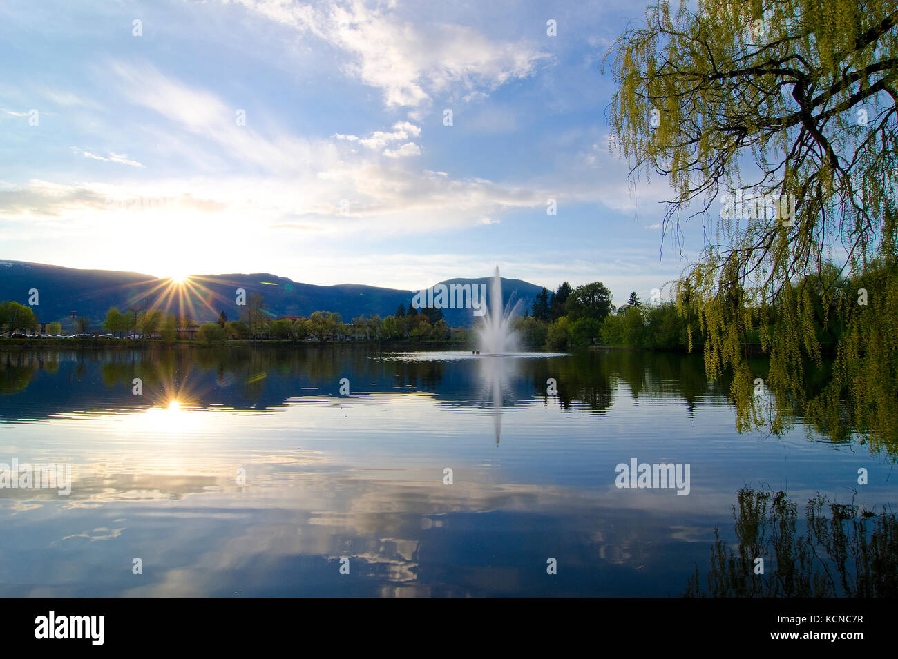 Le soleil se couche derrière les montagnes qui entourent la zone urbaine de McGuire Lake au coeur de Salmon Arm dans la région de Shuswap de la Colombie-Britannique, Canada Banque D'Images