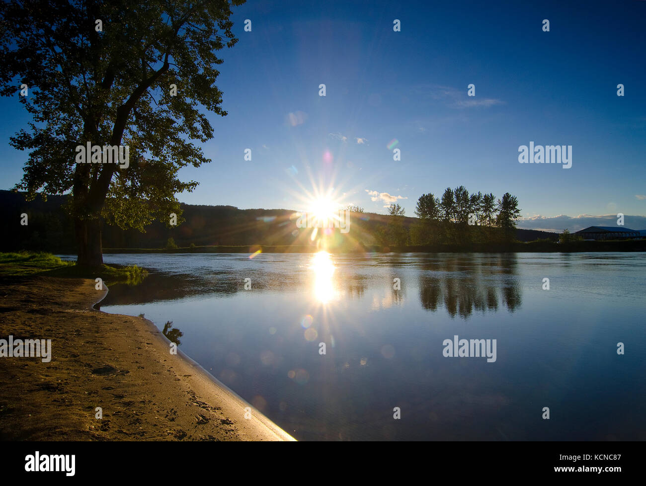 Le soleil du soir se couche derrière les montagnes qui entourent la rivière Shuswap à Enderby dans la région de Shuswap de la Colombie-Britannique, Canada Banque D'Images