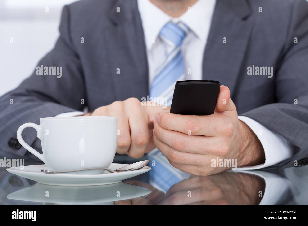 Close-up d'affaires Using Cellphone With Coffee Cup placé à 24 Banque D'Images