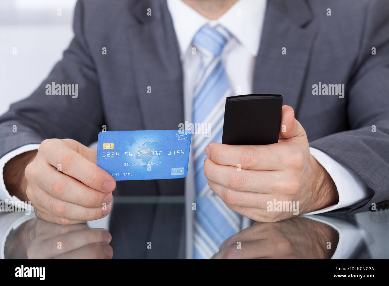 Close-up d'affaires à l'aide de Phone Card Sitting At Desk Banque D'Images