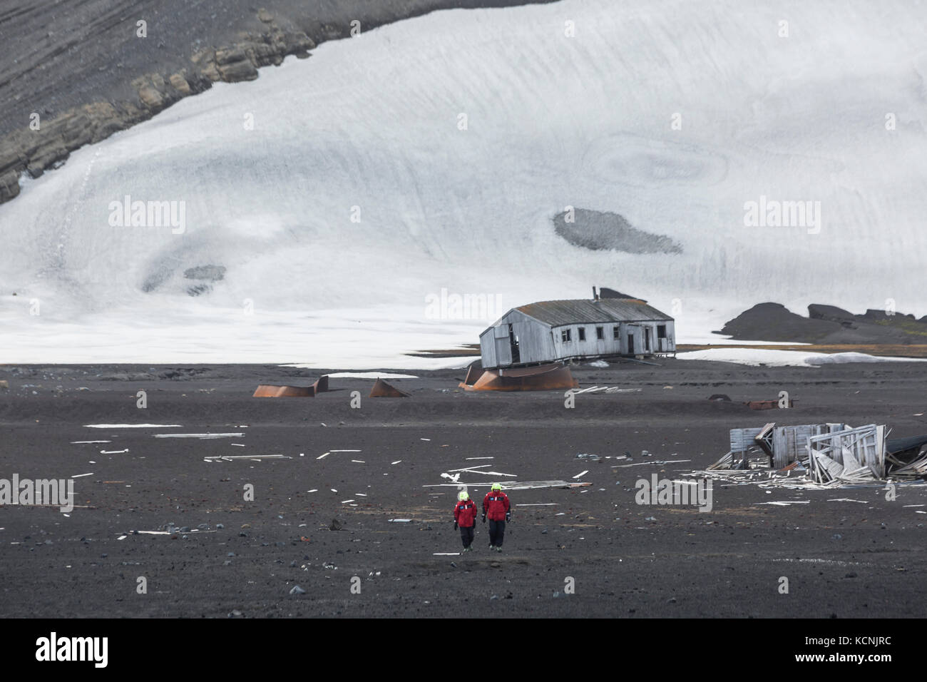 Deux touristes d'aventure à pied le long du paysage volcanique et deteriating les bâtiments de l'Île Déception, îles Shetland du Sud Banque D'Images