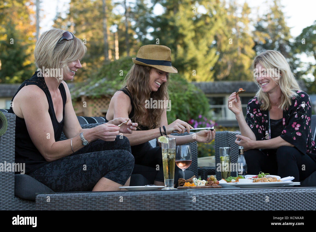 Trois copines se détendre à une terrasse extérieure tout en visitant le Kingfisher Resort et Spa. La vallée de Comox, Vancouver Island, British Columbia, Canada. Banque D'Images