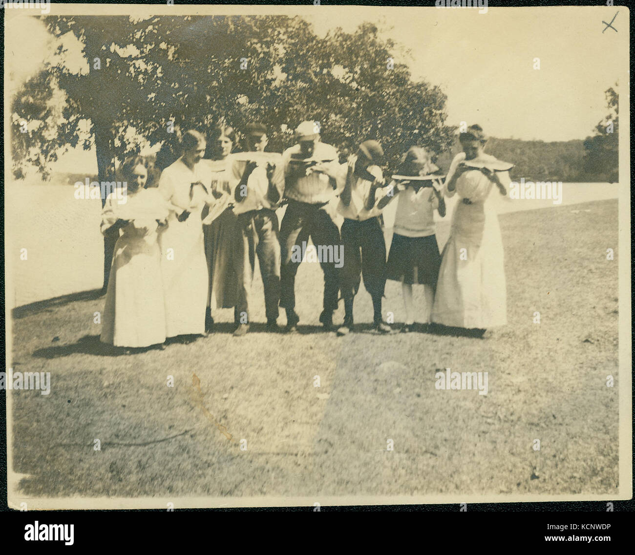 Groupe de jeunes hommes et femmes associés à la famille Lyon eating watermelon près d'un lac Banque D'Images