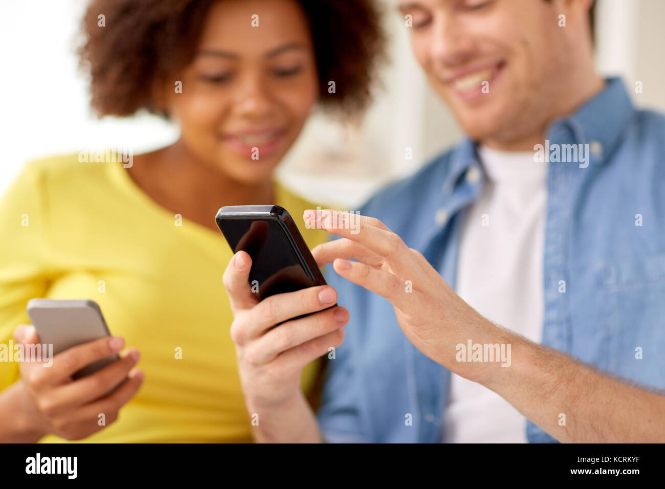 Couple heureux avec les smartphones à la maison Banque D'Images