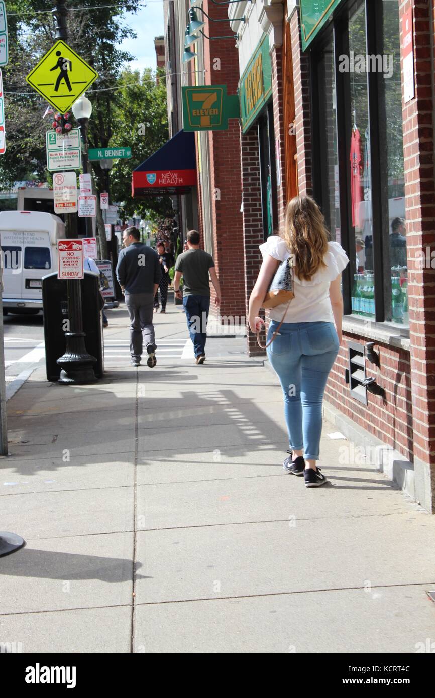 Une dame avec un gros cul marche dans une rue de la ville portant des jeans skinny et une belle chemise Banque D'Images