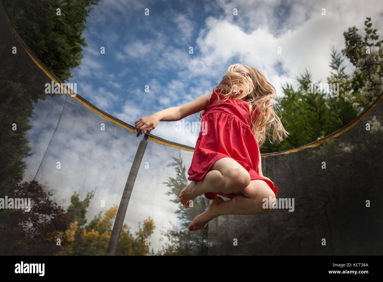 Girl jumping on trampoline Banque D'Images