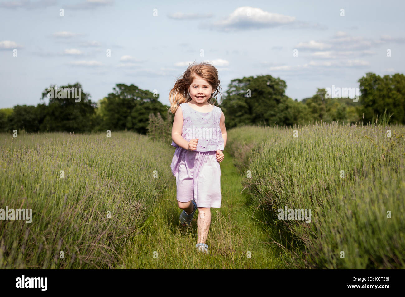 Little girl running through field Banque D'Images