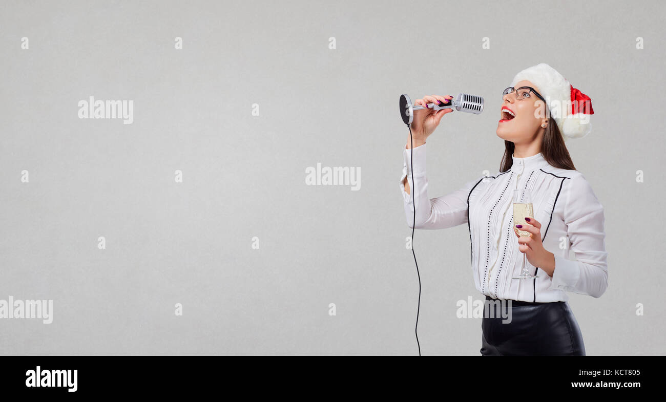 Une femme dans un santa claus hat chante un karaoké dans le microphone Banque D'Images