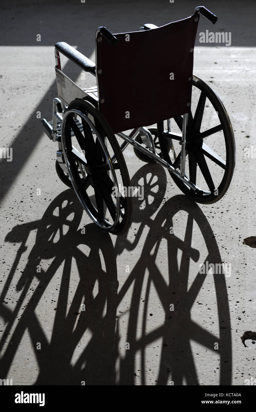 Un seul fauteuil roulant vide dans un bâtiment avec un sol en béton Banque D'Images