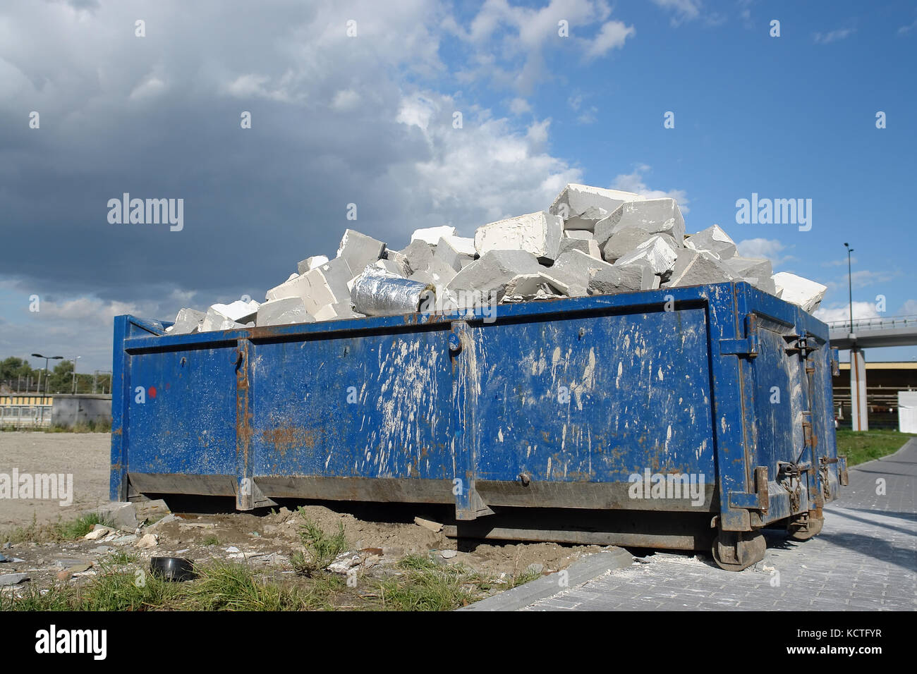 Conteneur de déchets de métal bleu avec des débris de construction Banque D'Images