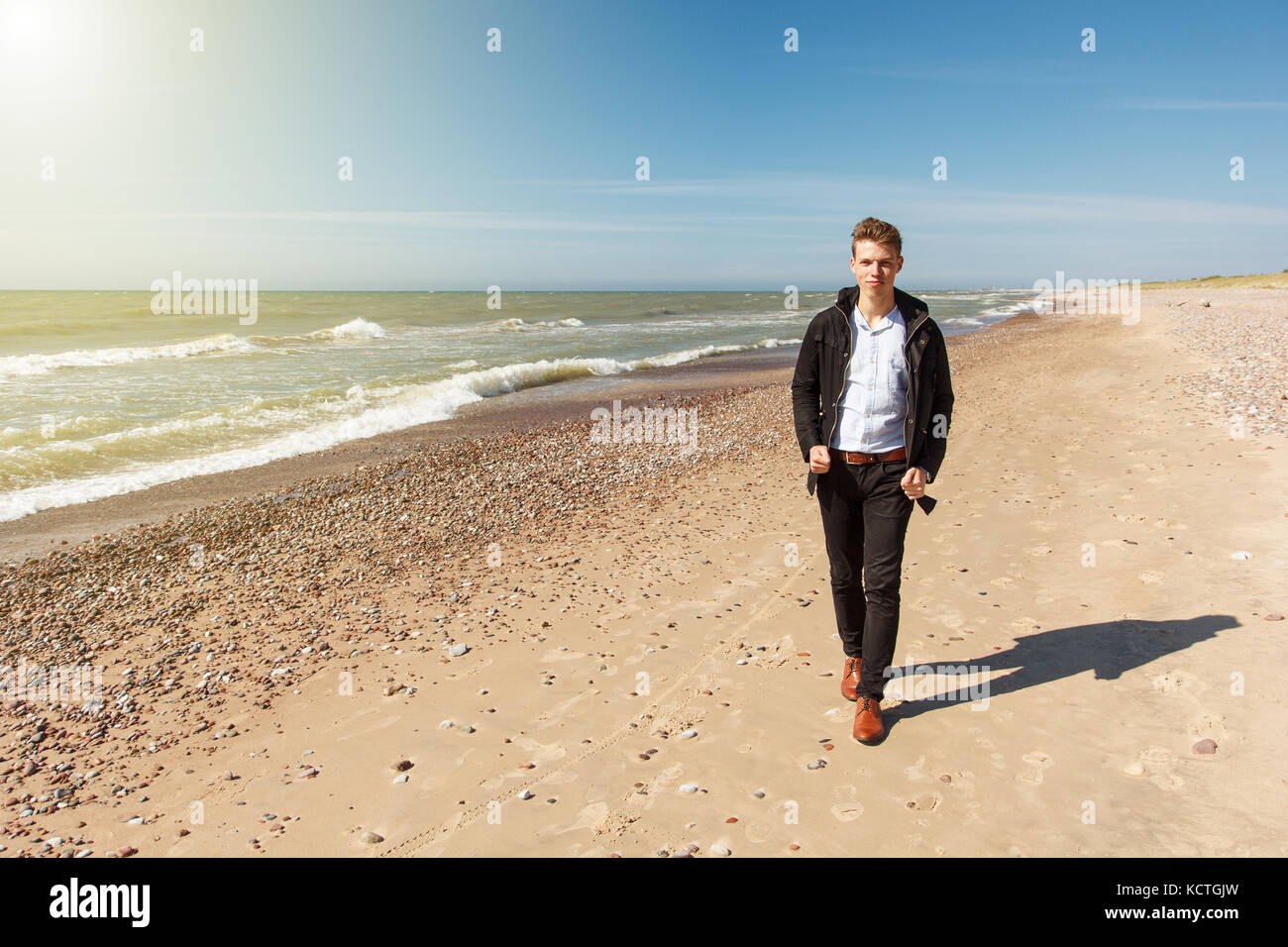 Un homme marchant le long d'une plage vide Banque D'Images