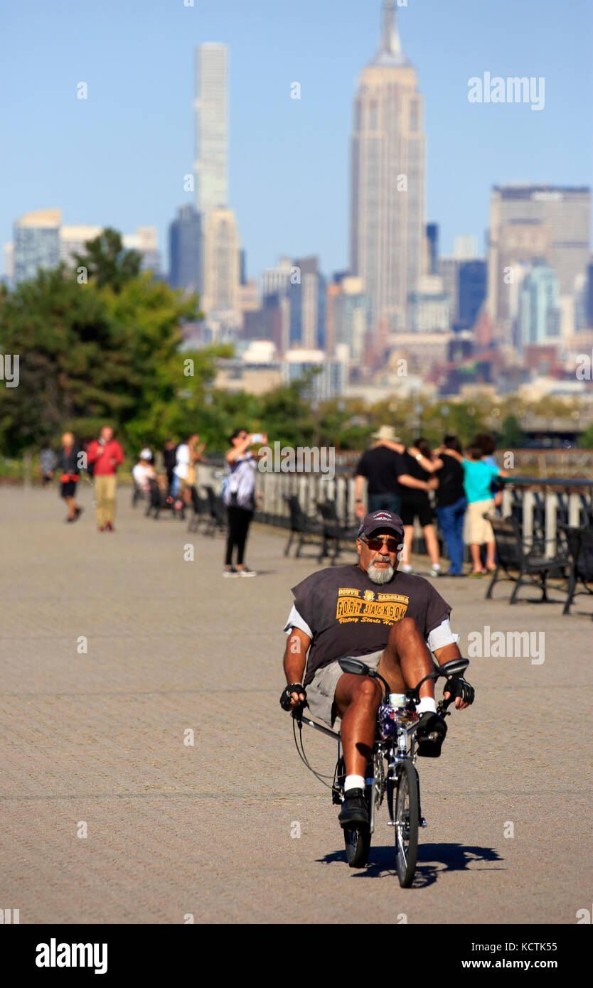 Un homme qui fait du vélo à position allongée dans Liberty State Park avec les gratte-ciel de Manhattan à New York et l'Empire State Building en arrière-plan.New Jersey, États-Unis Banque D'Images