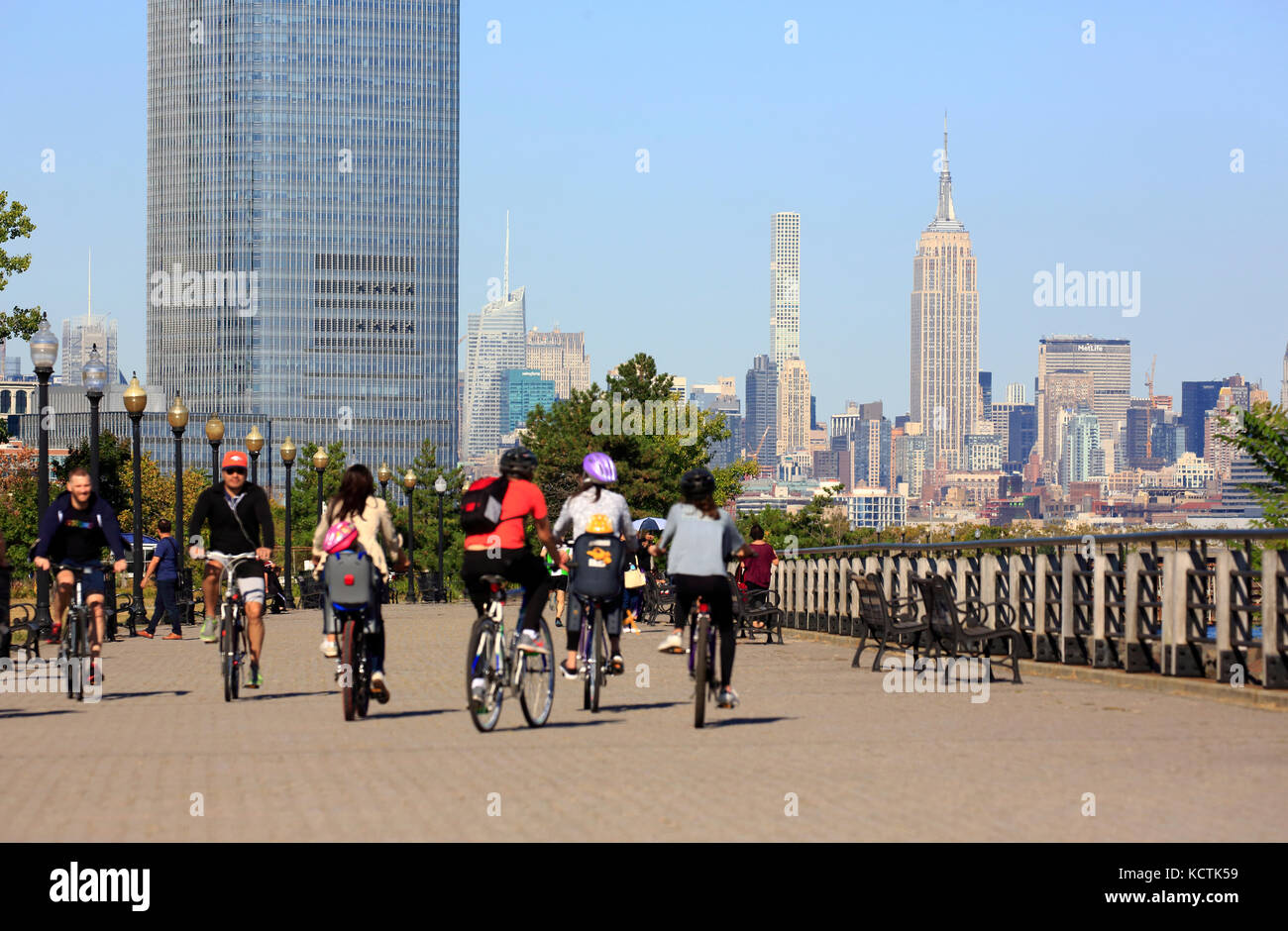 Visiteurs à vélo dans le parc national Liberty avec la tour Goldman Sachs et les gratte-ciel de Midtown Manhattan et l'Empire State Building en arrière-plan.New Jersey.USA Banque D'Images