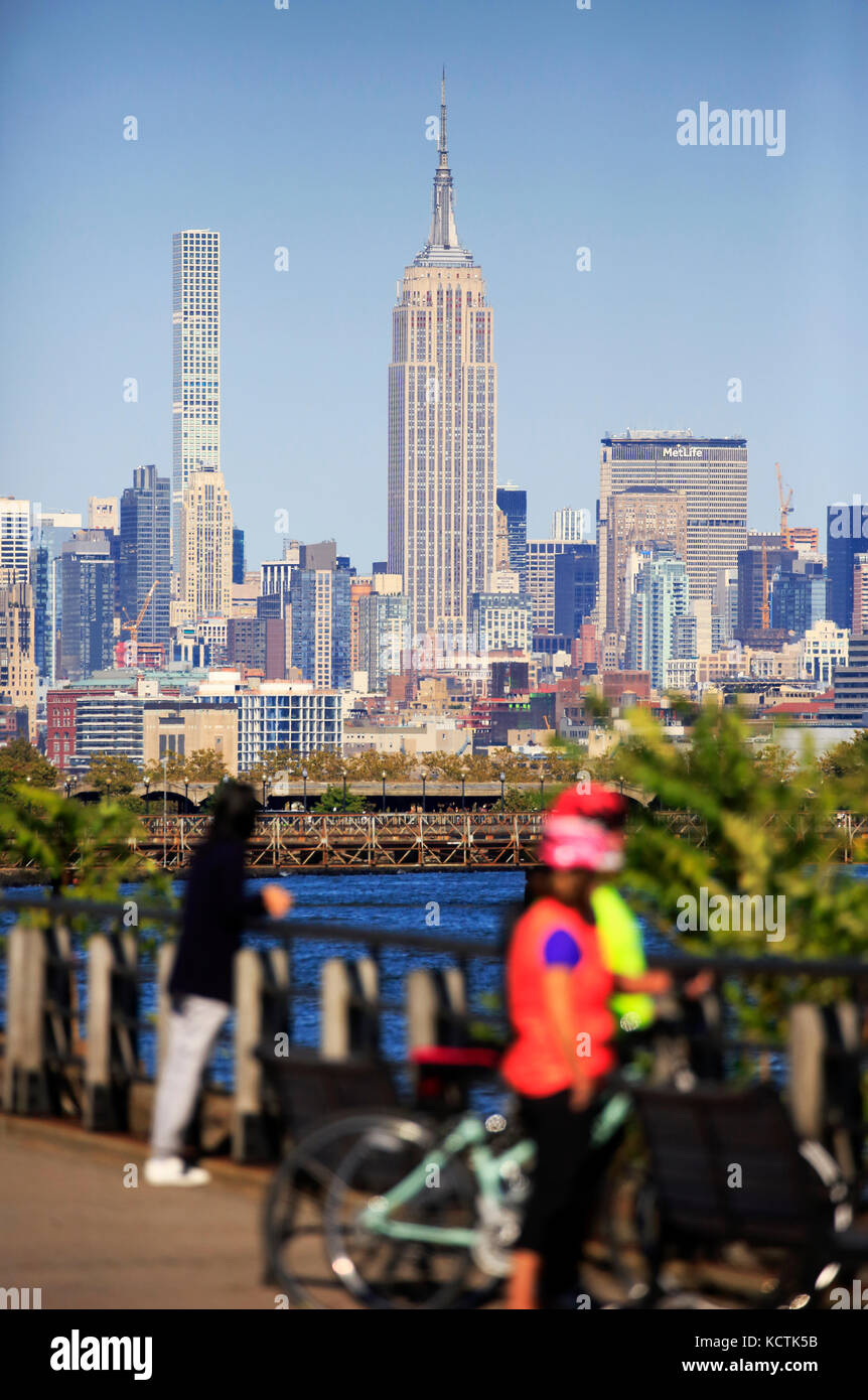 Visiteurs à la promenade du bord de mer de Hudson River dans le parc national Liberty avec le centre-ville de Manhattan à New York et l'Empire State Building en arrière-plan.NJ.USA Banque D'Images