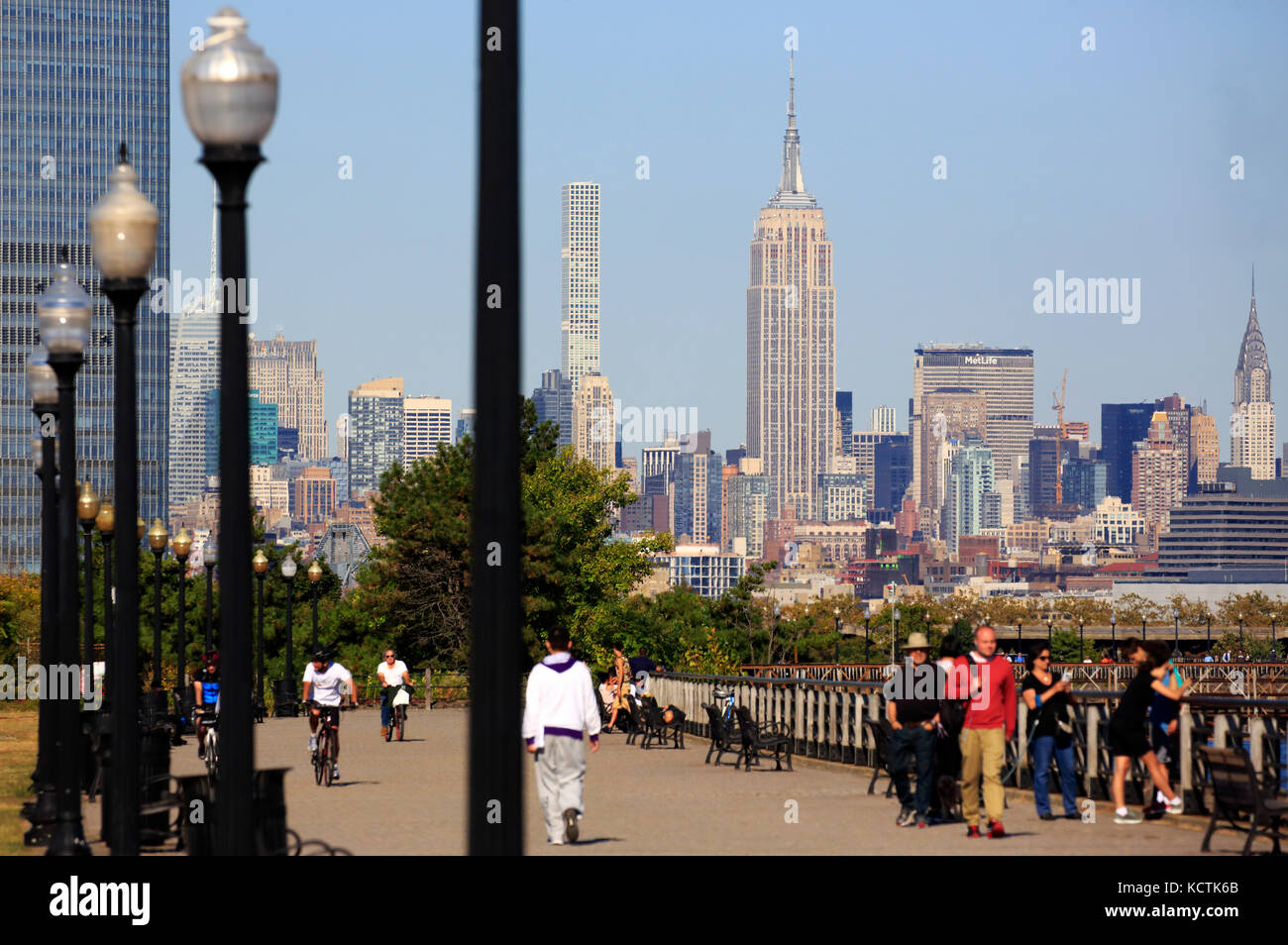 Visiteurs à la promenade du bord de mer de Hudson River dans le parc national Liberty avec le centre-ville de Manhattan à New York et l'Empire State Building en arrière-plan.NJ.USA Banque D'Images