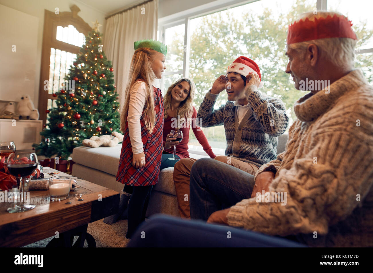 Famille heureuse à la maison wearing santa hat et couronne la veille de Noël. Petite fille avec ses parents et grands-parents de célébrer Noël. Banque D'Images