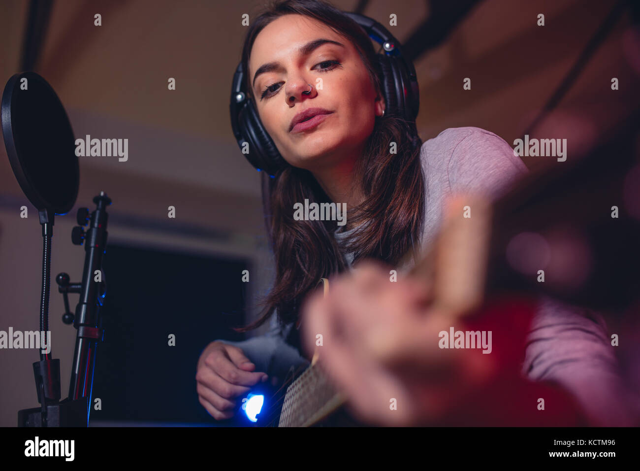 Guitariste femme jouant de la guitare dans un studio d'enregistrement. Chanteuse chantant une chanson en studio. Banque D'Images