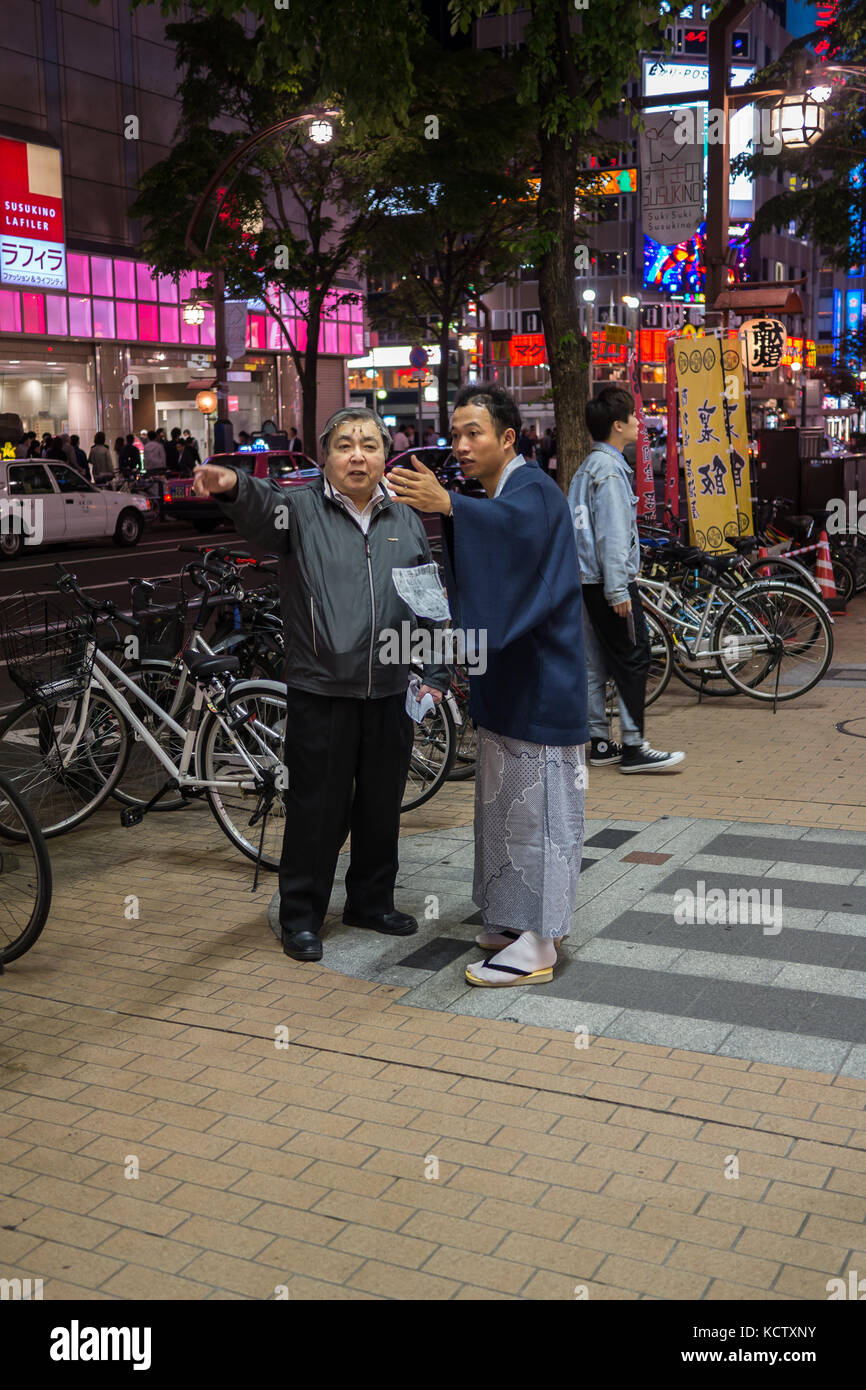 Jeune homme demandant à l'homme d'âge moyen pour les directions. les deux dans la même direction. jeune homme portant un kimono traditionnel japonais, chaussettes blanches. Banque D'Images