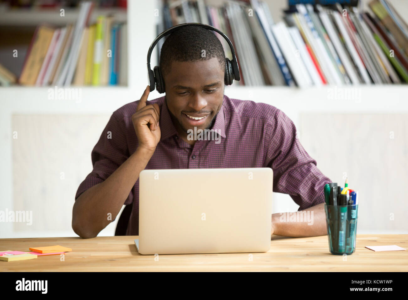 Smiling african american boy dans les écouteurs à la recherche à l'écran du portable. jeune businessman qui étudient les langues étrangères, la communication avec Banque D'Images