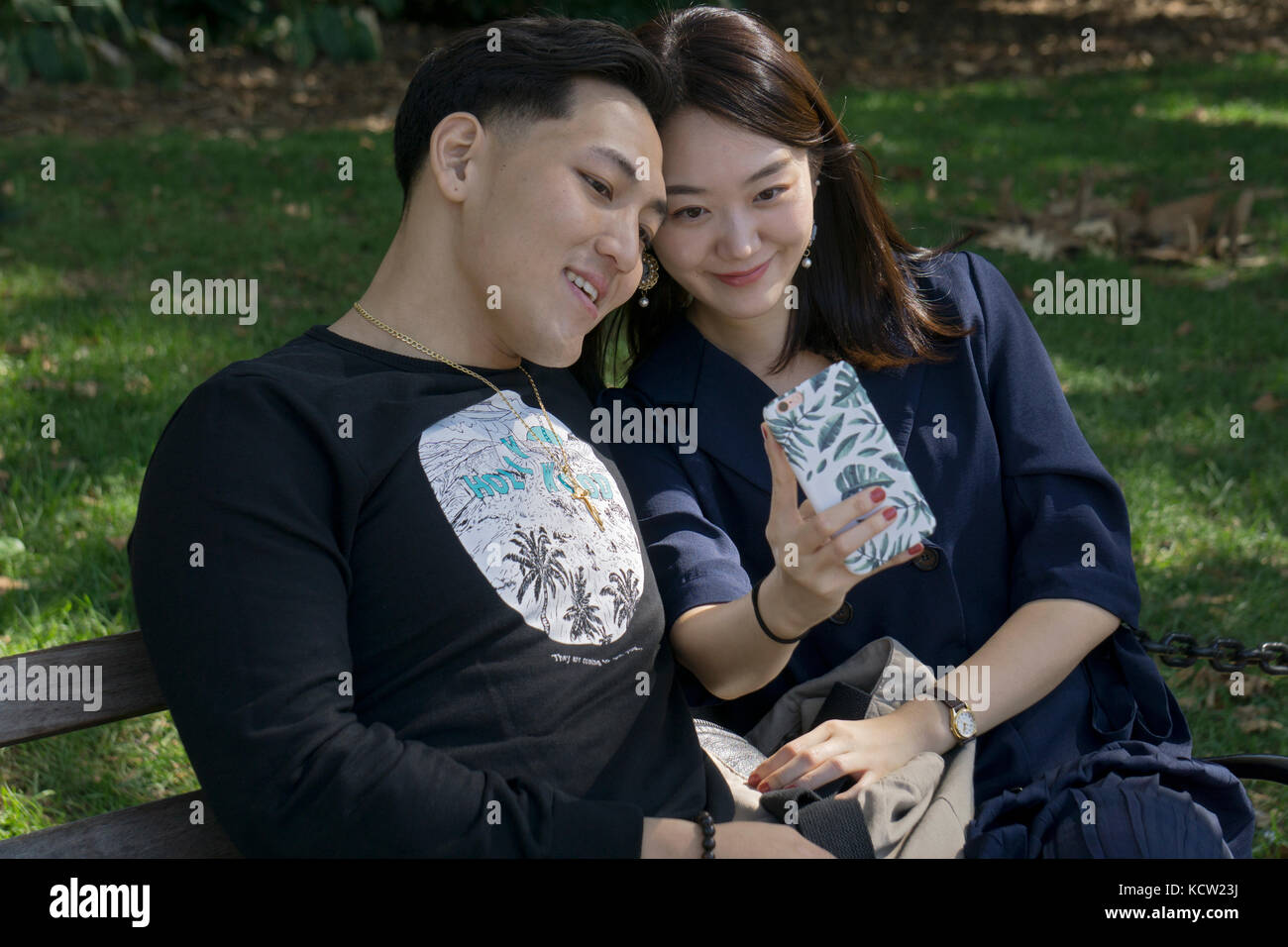 Deux coréens américains prendre un attrayant sur un banc de selfies Washington Square Park à Greenwich Village, New York City Banque D'Images
