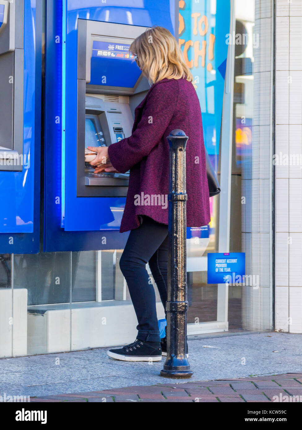 Une jeune femme blonde un retrait d'argent d'un GAB de la Banque Halifax ou Cash Machine Banque D'Images