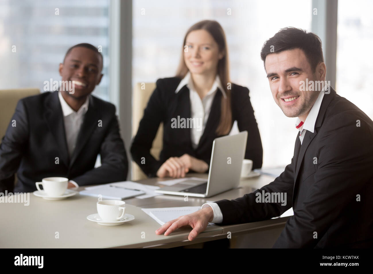 Portrait de friendly caucasian businessman sitting at table des négociations avec des collègues ou des partenaires lors de la réunion de l'équipe d'interracial. Banque D'Images