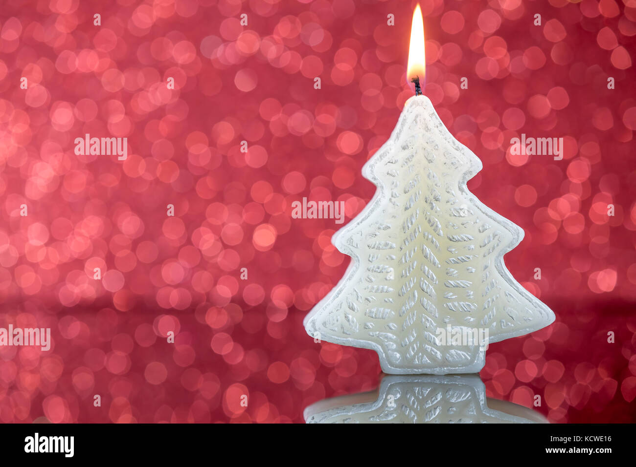 La lumière des bougies de l'arbre de Noël avec la réflexion sur l'arrière-plan flou floue rouge. Banque D'Images