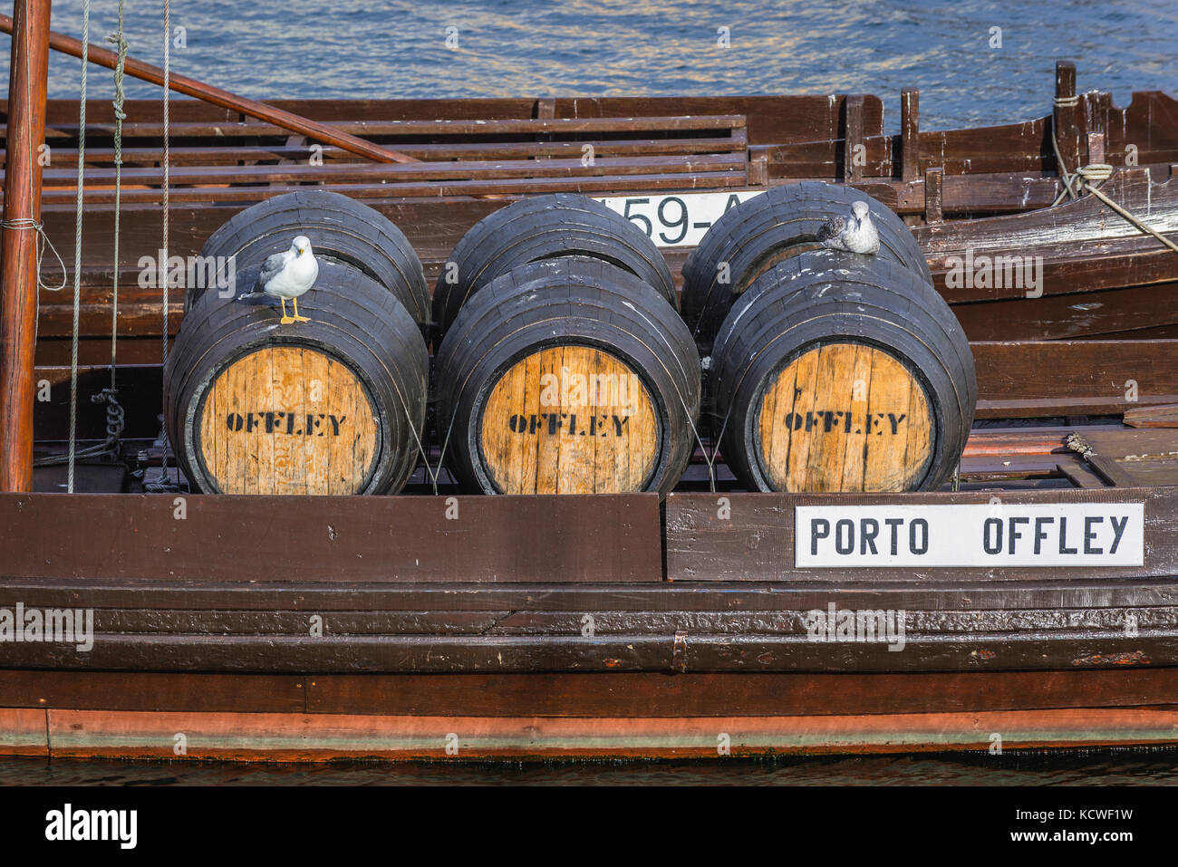 Des fûts sur un bateau à vin Offley Port appelé Rabelo Boats sur un fleuve Douro dans la ville de Vila Nova de Gaia. Porto City River Bank en arrière-plan Banque D'Images