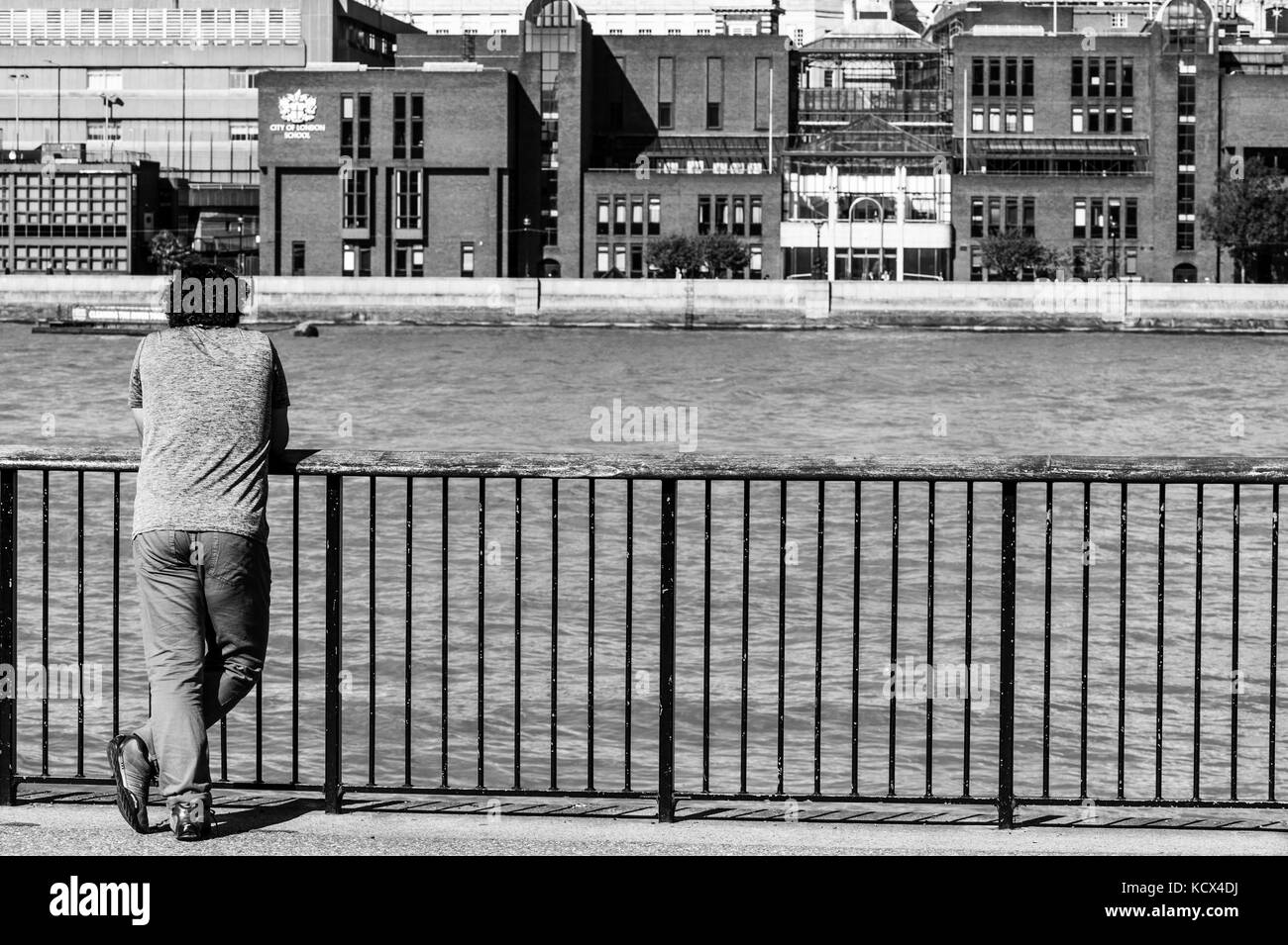 Portrait noir et blanc monochrome d'un homme avec son dos à l'appareil photo en regardant la Tamise à Londres, le gouvernement de Coronavirus a verrouillé Banque D'Images