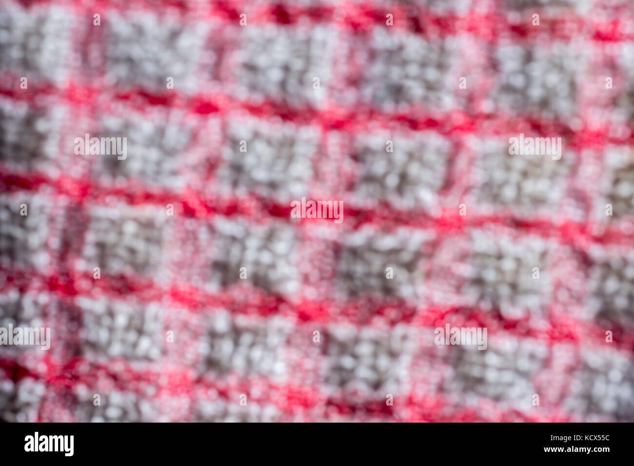 Adouci, floue, close-up plan macro sur la chaîne et la trame d'un teacloth rouge et blanc. Banque D'Images