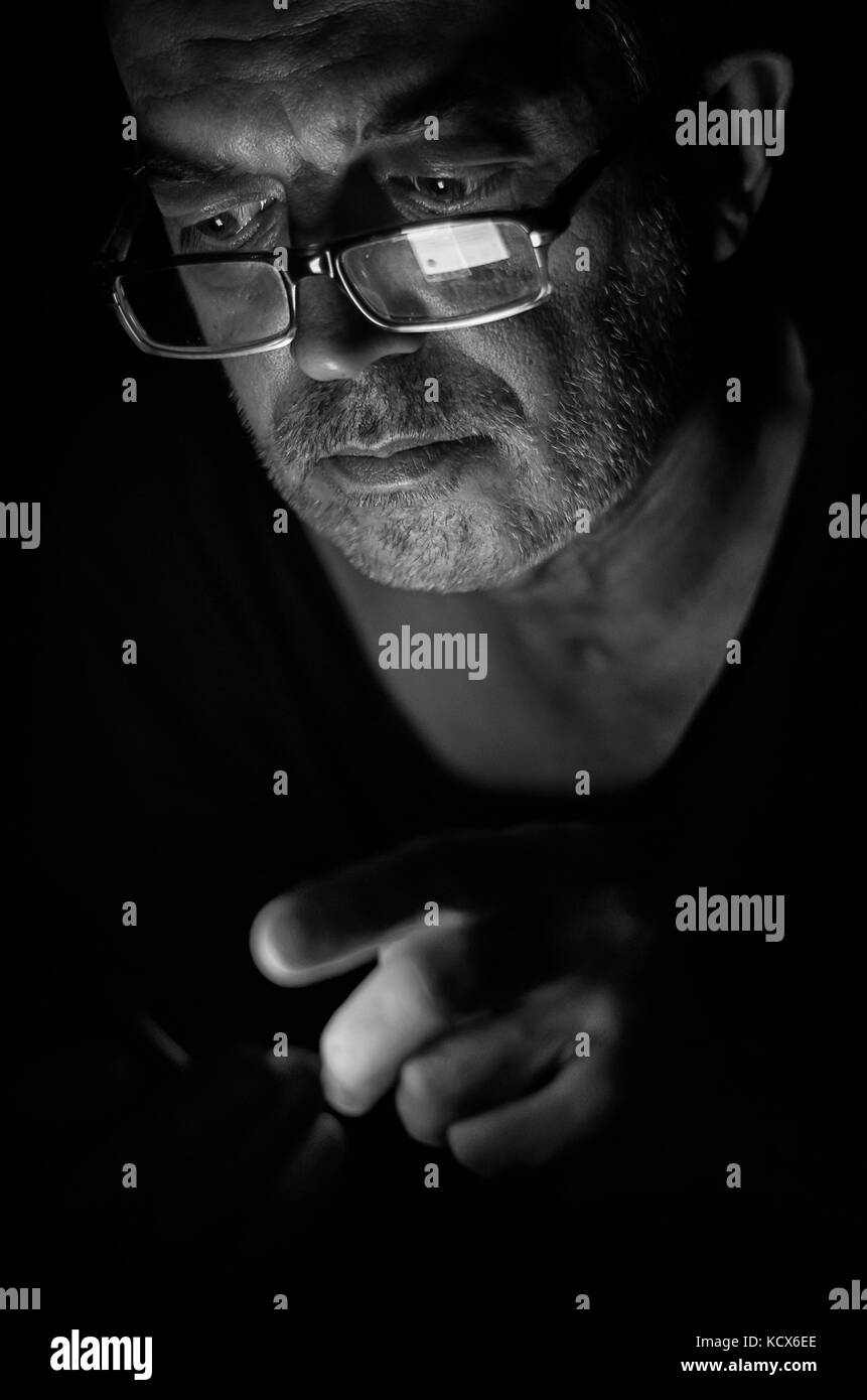 Portrait d'un homme âgé avec un smartphone dans l'obscurité. Banque D'Images