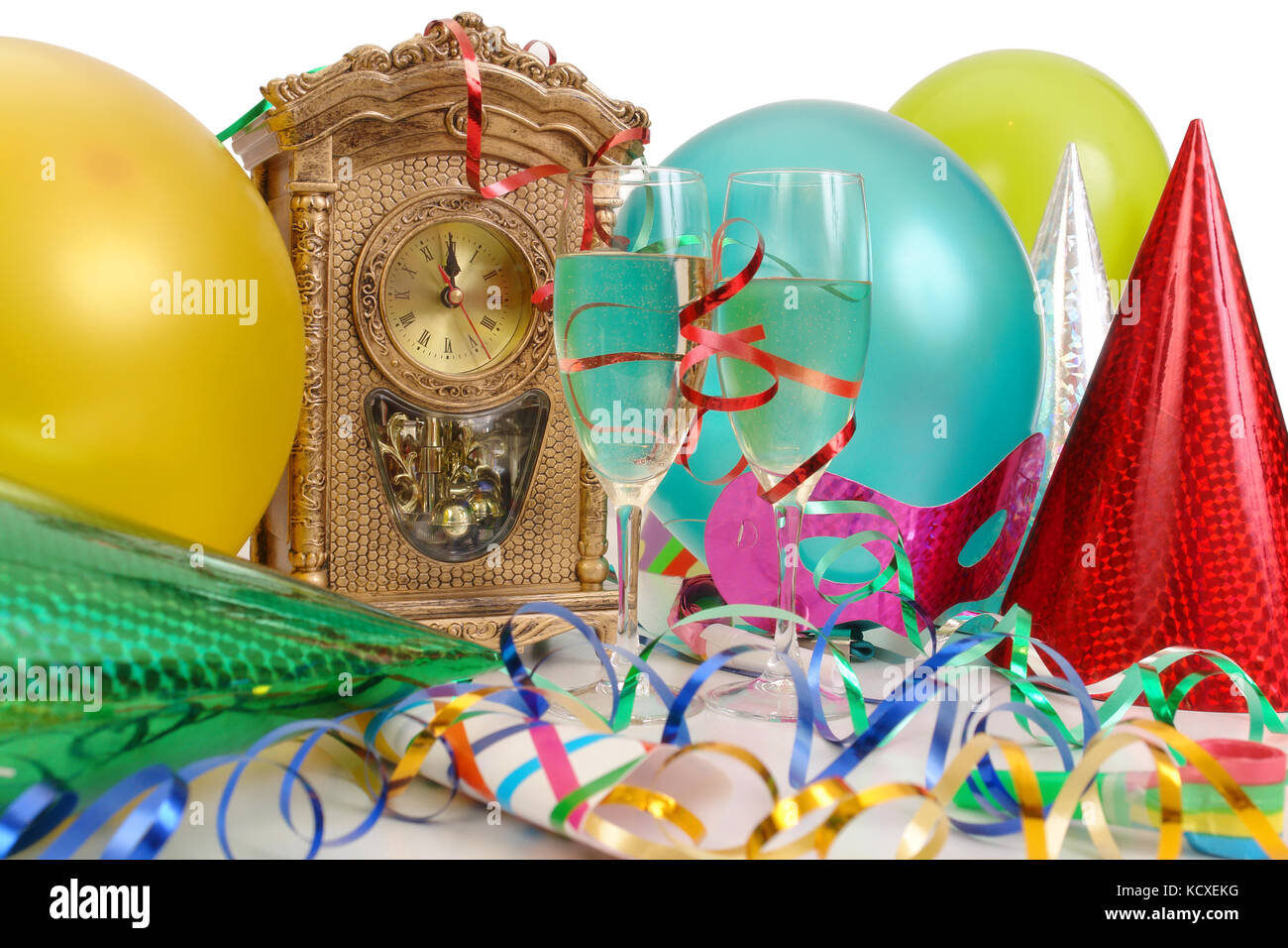 Horloge de table montrant presque nouvelle an, banderoles, ballons, chapeaux de fête et deux verres de champagne Banque D'Images
