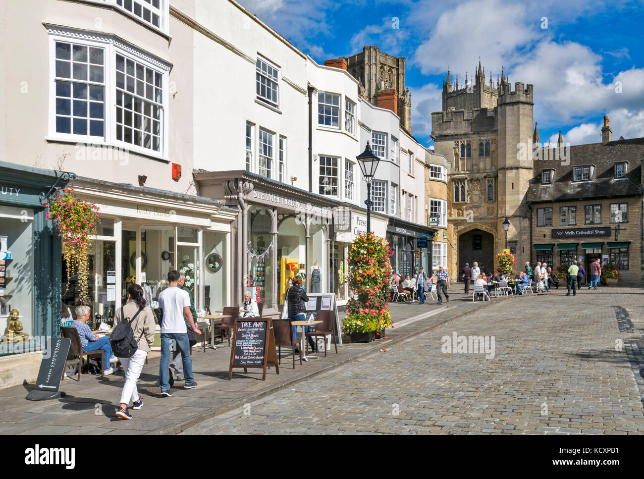 WELLS SOMERSET ANGLETERRE RUE PRINCIPALE MENANT À LA CATHÉDRALE sur un matin ensoleillé avec des tables à café en plein air Banque D'Images