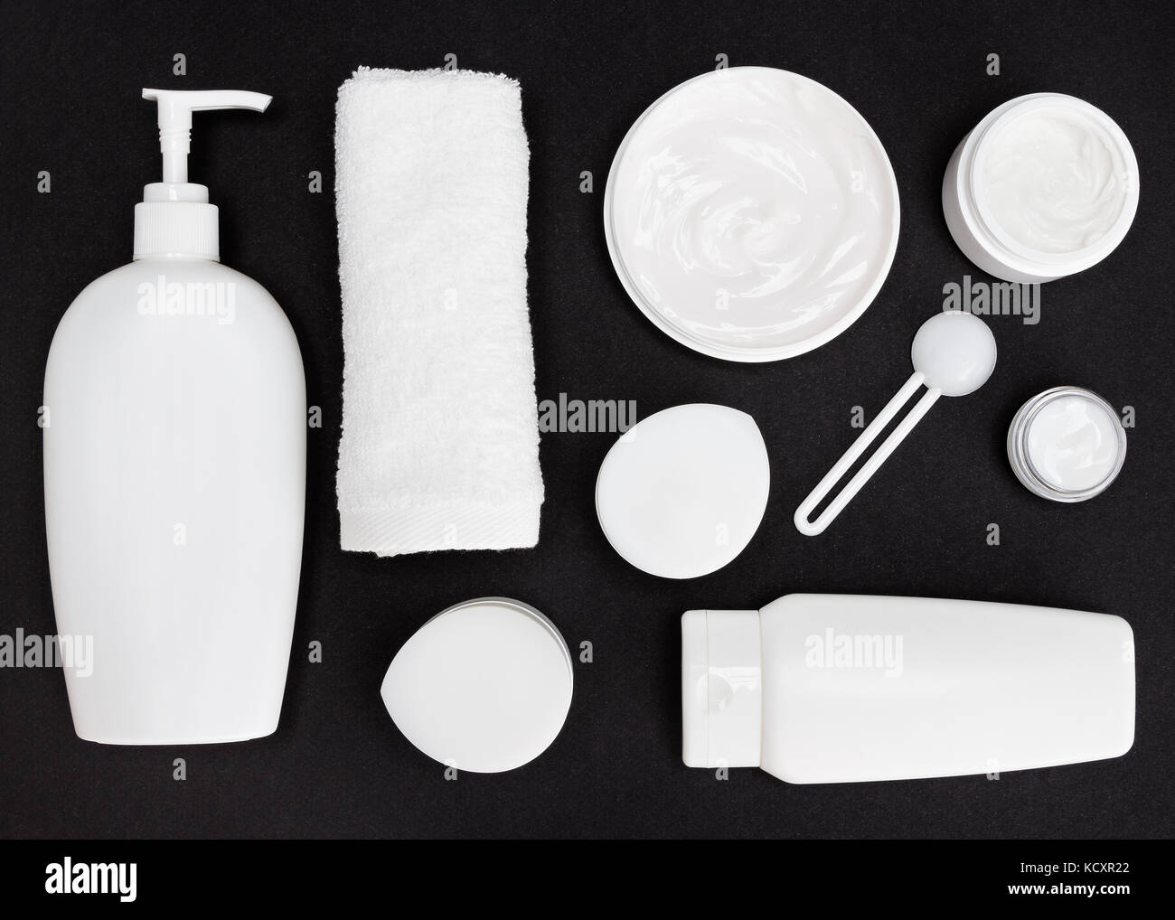 Contenants cosmétiques blanc et Terry serviettes sur la surface noire. divers produits cosmétiques pour les soins de la peau. nettoyant, masque et le corps, le visage, l'oeil écrème Banque D'Images