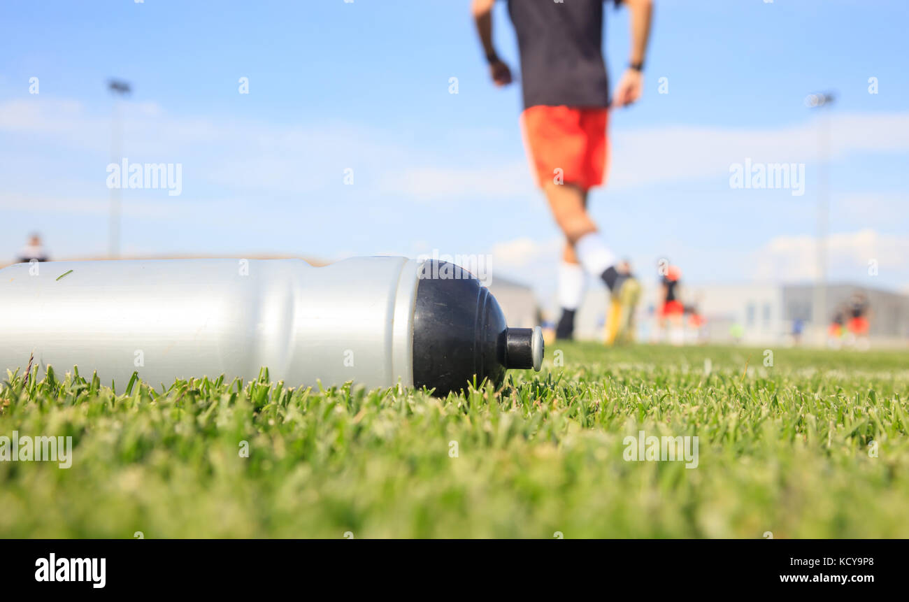 Bouteille de sport d'eau douce de boisson énergétique sur terrain de football gazon. Banque D'Images