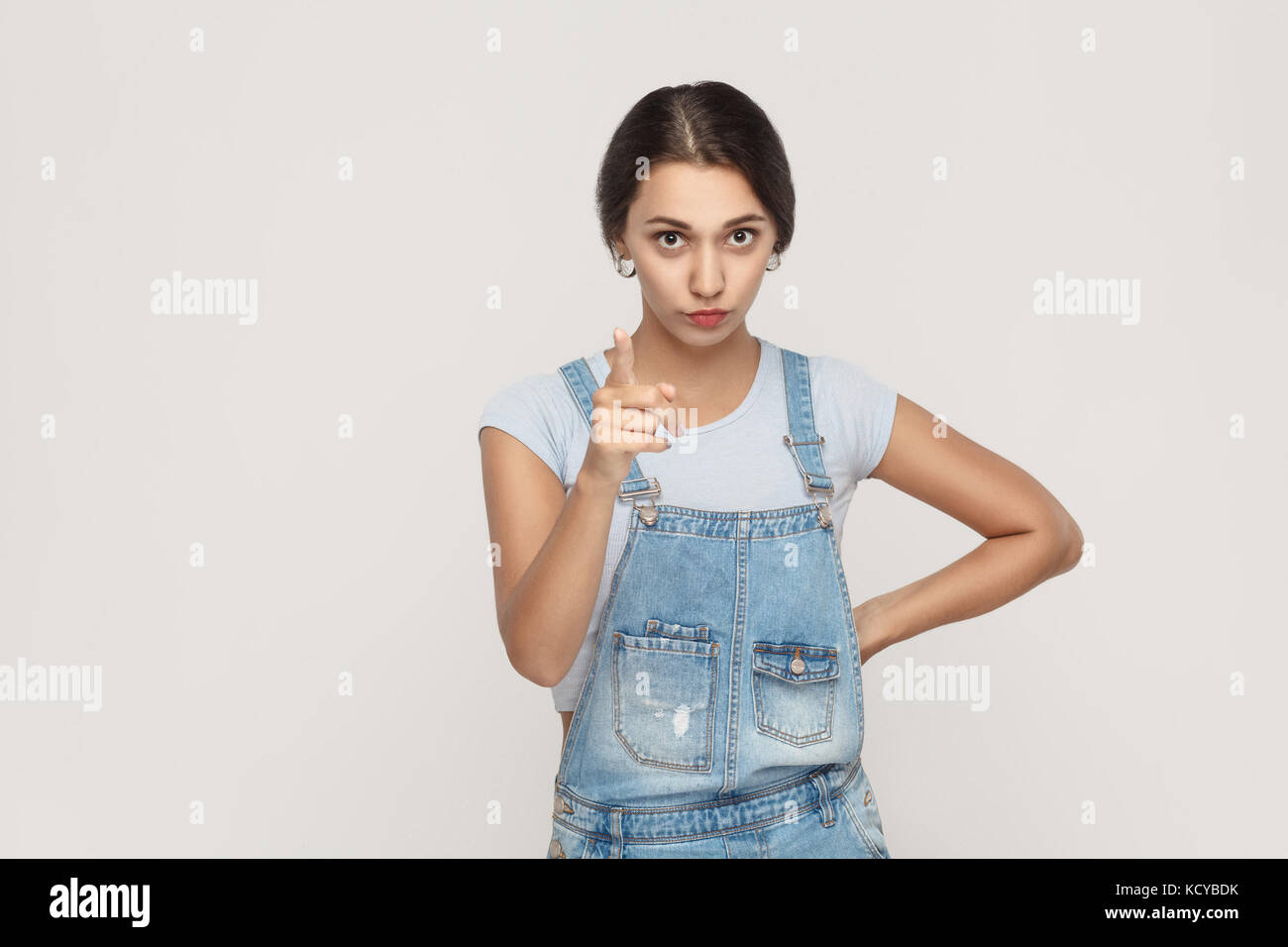 Panneau d'avertissement. les jeunes des profils middle eastern woman, looking at camera avec sérieux et doigt avertissement. studio shot. fond gris. Banque D'Images