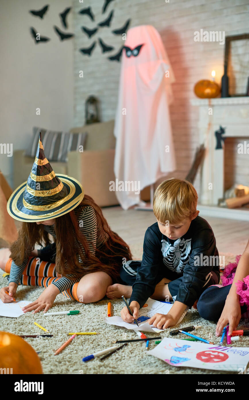 Portrait de trois enfants vêtus de costumes de Halloween dimensions assis sur le plancher en studio décoré Banque D'Images