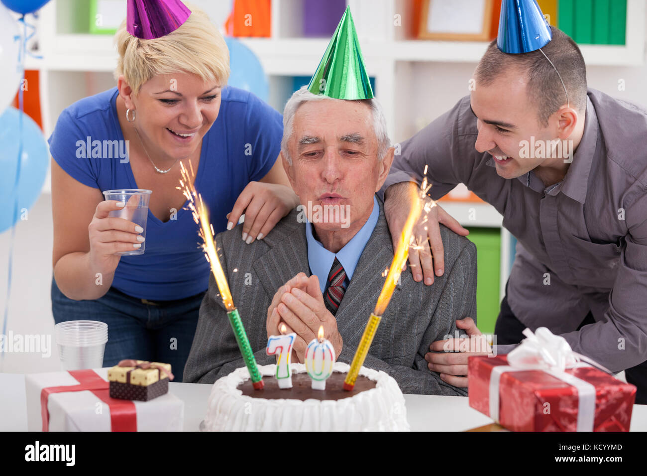 Senior man blowing candles avec famille et amis Banque D'Images