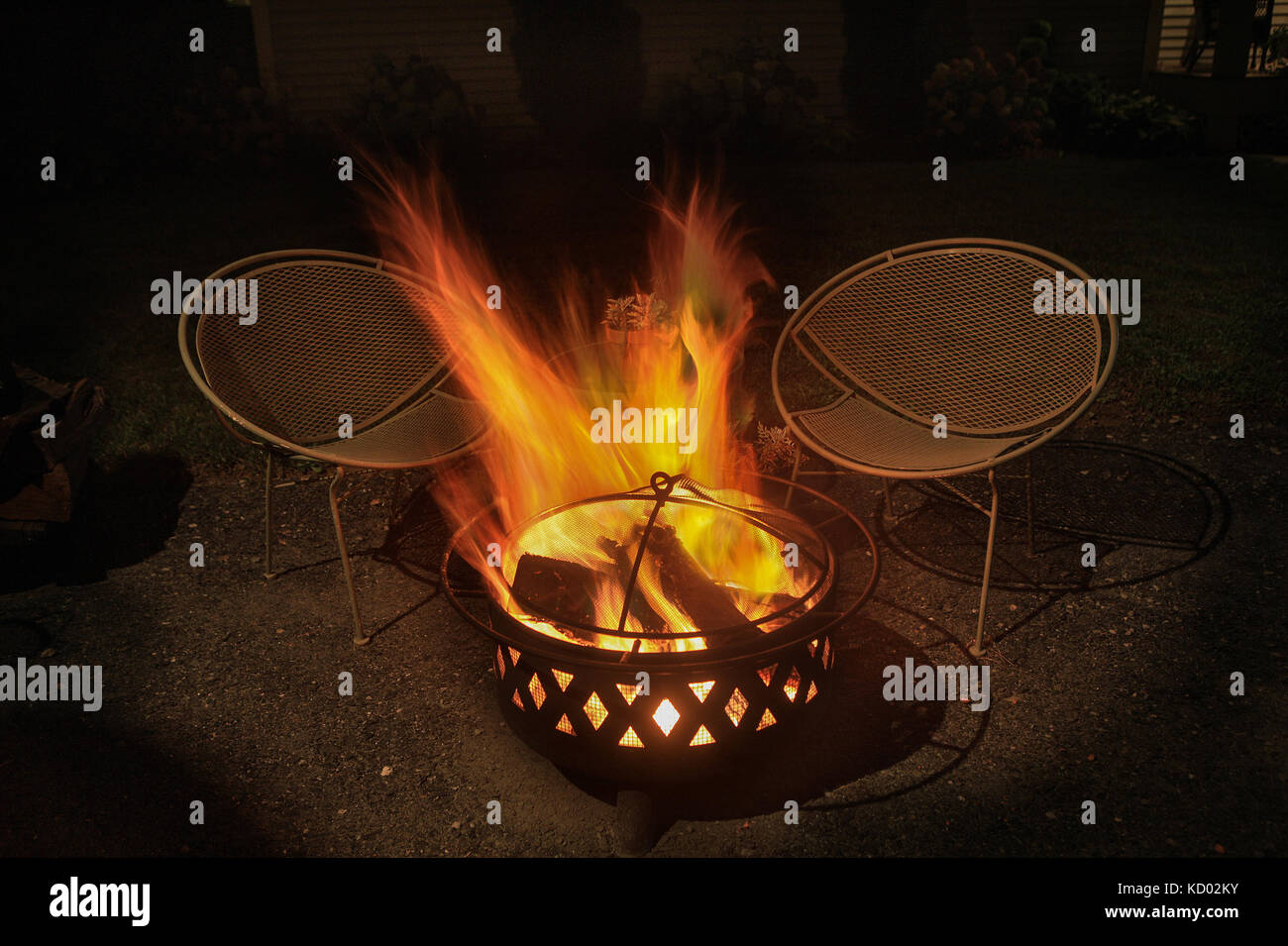 Accumuler les flammes d'un fer à repasser brûlant de feu à côté de deux chaises dans la nuit. Banque D'Images