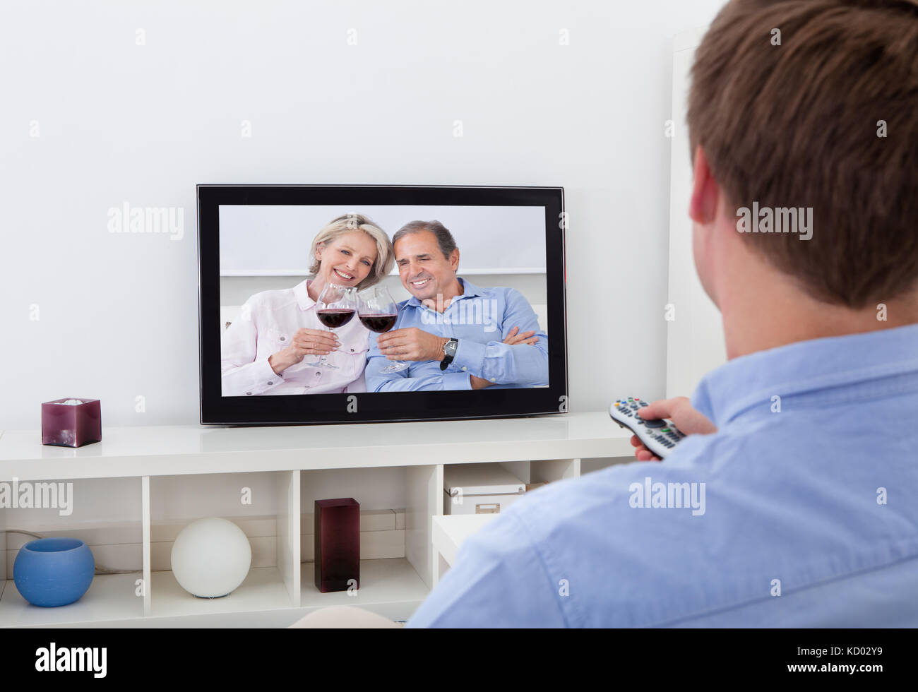 Vue arrière d'un homme assis sur le canapé à regarder la télévision Banque D'Images