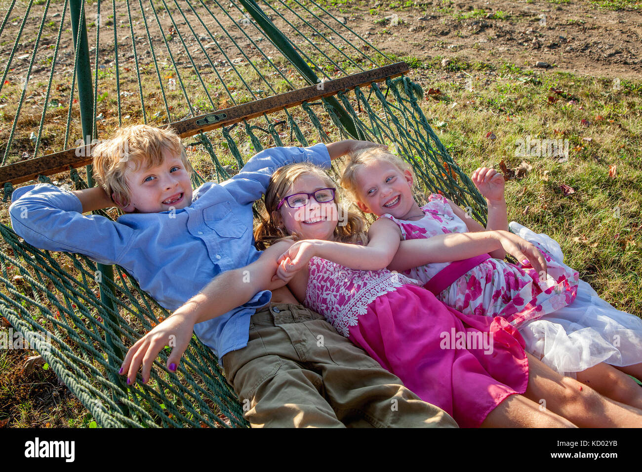Trois enfants heureux balançant ensemble sur un hamac. Banque D'Images